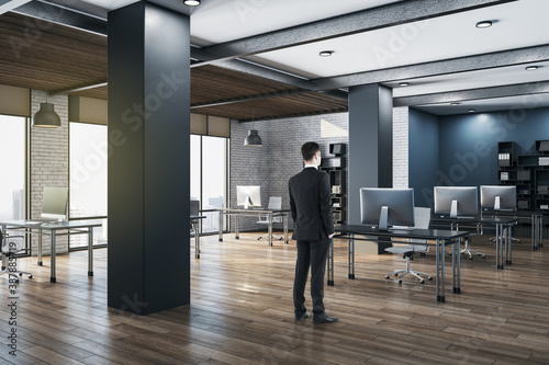 Businessman standing in panoramic open space modern office