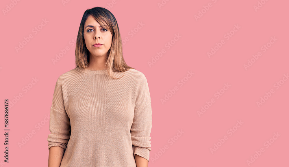 Young beautiful woman wearing casual sweater with serious expression on face. simple and natural looking at the camera. Young beautiful woman wearing casual sweater with serious expression on face. simple and natural looking at the camera.