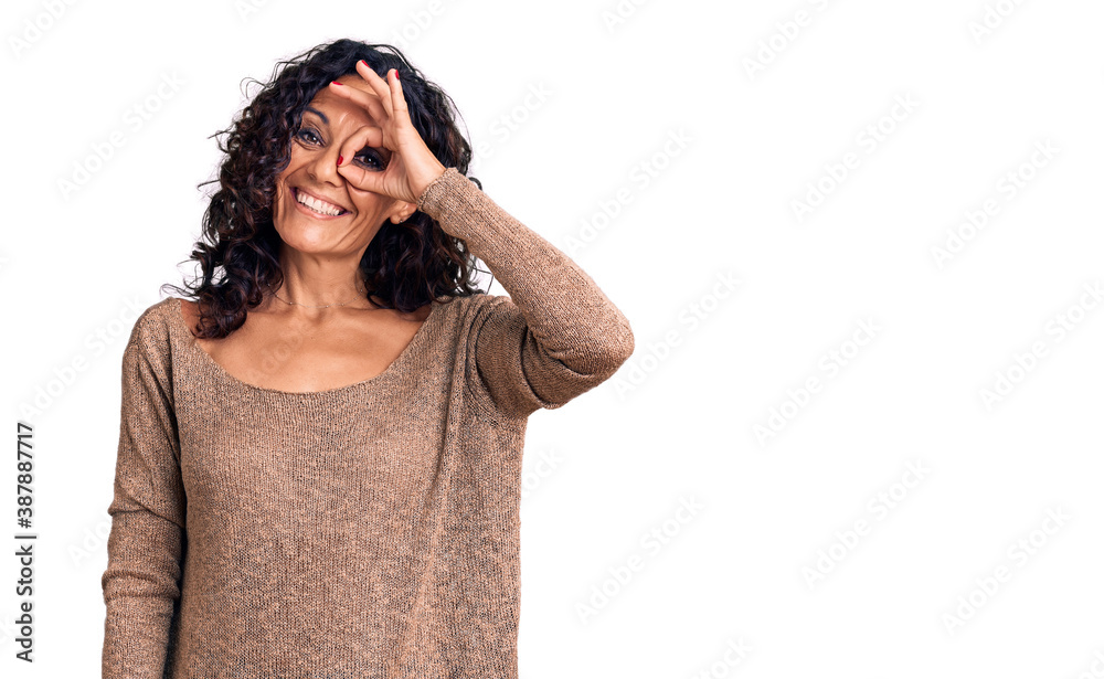 Middle age beautiful woman wearing casual sweater smiling happy doing ok sign with hand on eye looking through fingers Middle age beautiful woman wearing casual sweater smiling happy doing ok sign with hand on eye looking through fingers