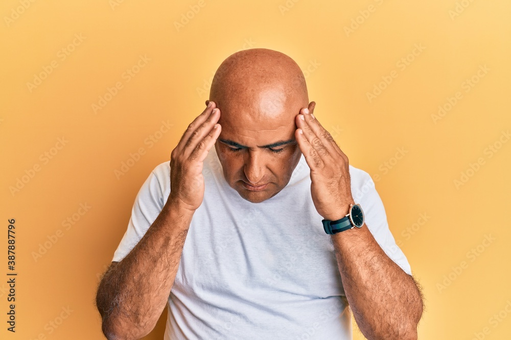 Obraz premium Mature middle east man wearing casual white tshirt with hand on head for pain in head because stress. suffering migraine.