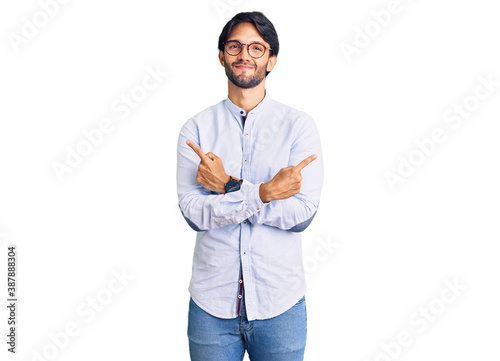 Handsome hispanic man wearing business shirt and glasses pointing to both sides with fingers, different direction disagree photo