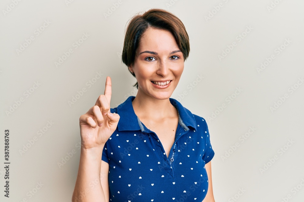 Young brunette woman with short hair wearing casual clothes smiling with an idea or question pointing finger up with happy face, number one Young brunette woman with short hair wearing casual clothes smiling with an idea or question pointing finger up with happy face, number one