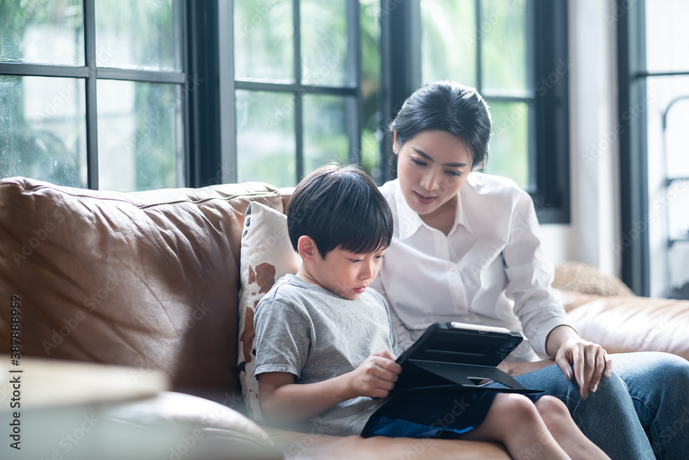 Asian mother teaching daughter learning online class on tablet. Asian mother teaching daughter learning online class on tablet.