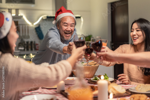 Asian big family clinking wine glasses and enjoying Christmas party.