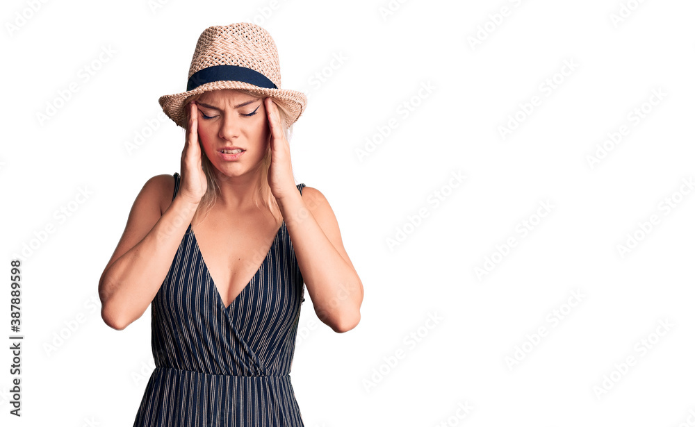 Young beautiful blonde woman wearing summer hat and dress with hand on head for pain in head because stress. suffering migraine. Young beautiful blonde woman wearing summer hat and dress with hand on head for pain in head because stress. suffering migraine.