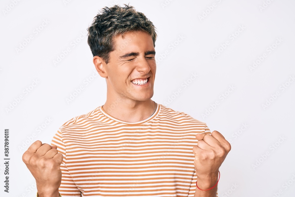 Young handsome man wearing casual clothes very happy and excited doing winner gesture with arms raised, smiling and screaming for success. celebration concept. Young handsome man wearing casual clothes very happy and excited doing winner gesture with arms raised, smiling and screaming for success. celebration concept.