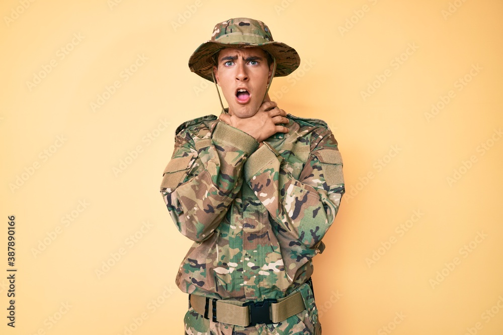 Young handsome man wearing camouflage army uniform shouting and suffocate because painful strangle. health problem. asphyxiate and suicide concept. Young handsome man wearing camouflage army uniform shouting and suffocate because painful strangle. health problem. asphyxiate and suicide concept.