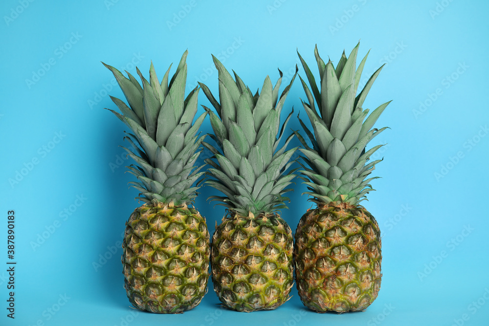 Ripe juicy pineapples on light blue background