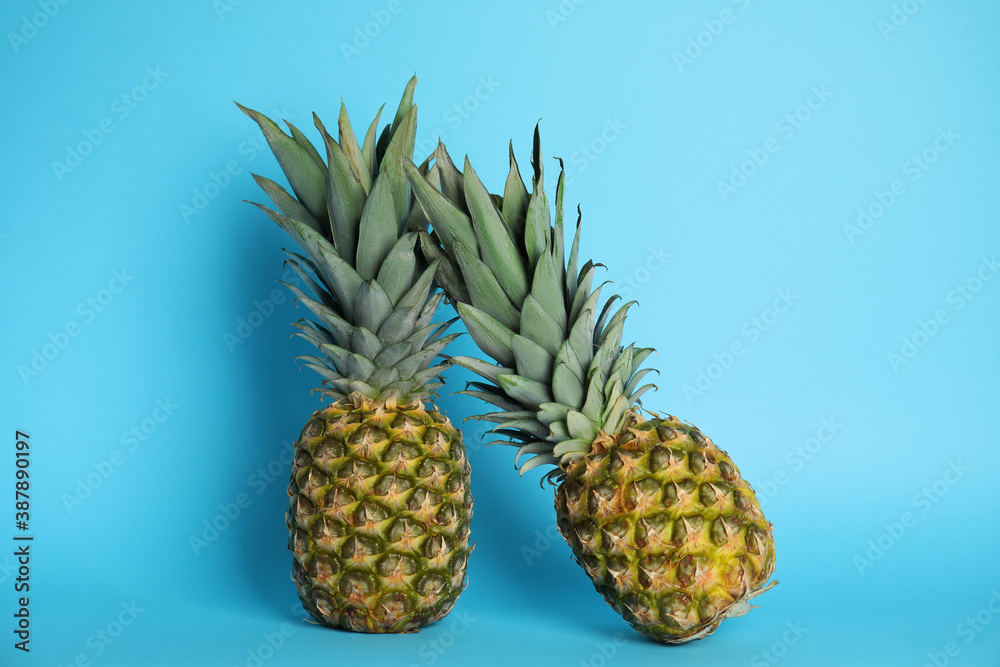 Ripe juicy pineapples on light blue background