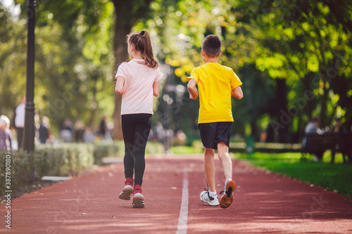 Kids run. Healthy sport. Child sport, heterosexual twins running on track, fitness. Joint training. Running training outdoor brother and sister pre-teen. Jogging with friend. Children athletes