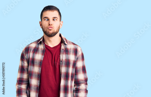 Young handsome man wearing casual shirt making fish face with lips, crazy and comical gesture. funny expression.