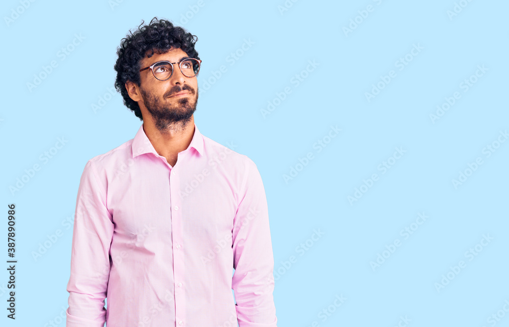 Handsome young man with curly hair and bear wearing business clothes smiling looking to the side and staring away thinking. Handsome young man with curly hair and bear wearing business clothes smiling looking to the side and staring away thinking.