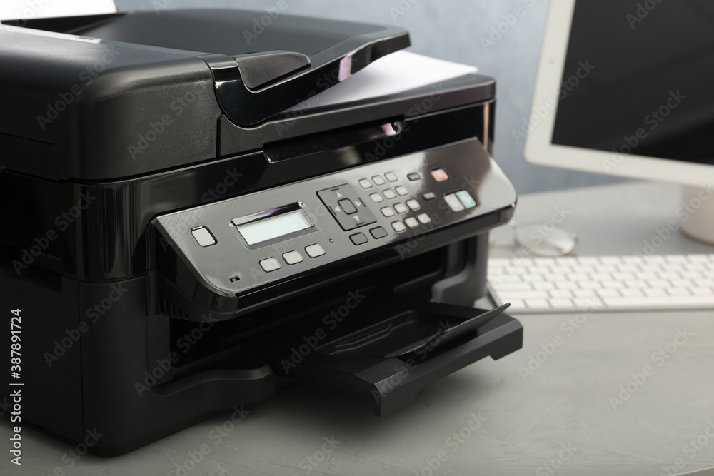 Modern printer with paper on grey table, closeup Modern printer with paper on grey table, closeup