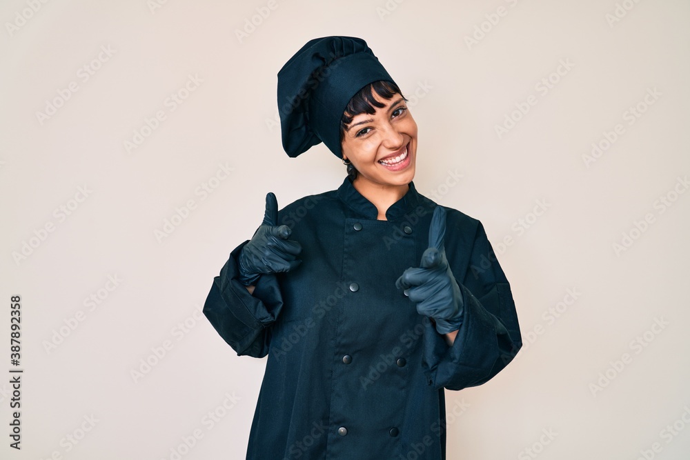 Beautiful brunettte woman wearing professional cook uniform pointing fingers to camera with happy and funny face. good energy and vibes. Beautiful brunettte woman wearing professional cook uniform pointing fingers to camera with happy and funny face. good energy and vibes.