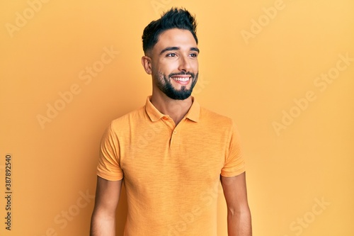 Young man with beard wearing casual clothes looking to side, relax profile pose with natural face and confident smile.