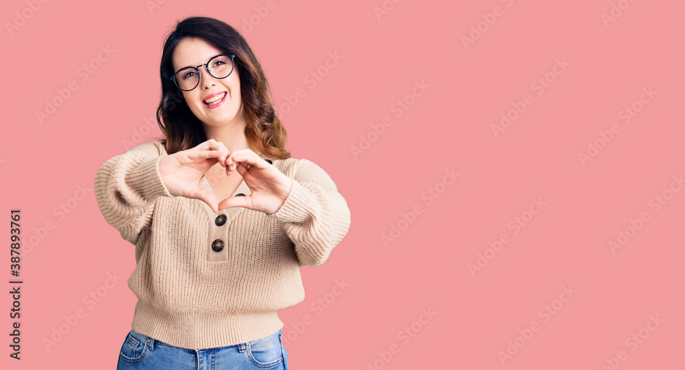 Beautiful young brunette woman wearing casual clothes and glasses smiling in love doing heart symbol shape with hands. romantic concept. Beautiful young brunette woman wearing casual clothes and glasses smiling in love doing heart symbol shape with hands. romantic concept.