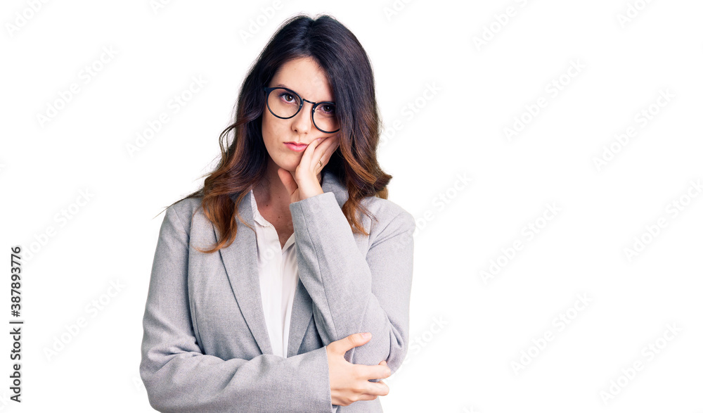 Beautiful young brunette woman wearing business clothes and glasses thinking looking tired and bored with depression problems with crossed arms. Beautiful young brunette woman wearing business clothes and glasses thinking looking tired and bored with depression problems with crossed arms.