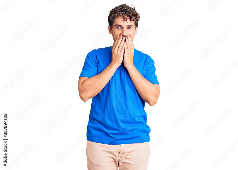 Young handsome man with curly hair wearing casual clothes laughing and embarrassed giggle covering mouth with hands, gossip and scandal concept Young handsome man with curly hair wearing casual clothes laughing and embarrassed giggle covering mouth with hands, gossip and scandal concept