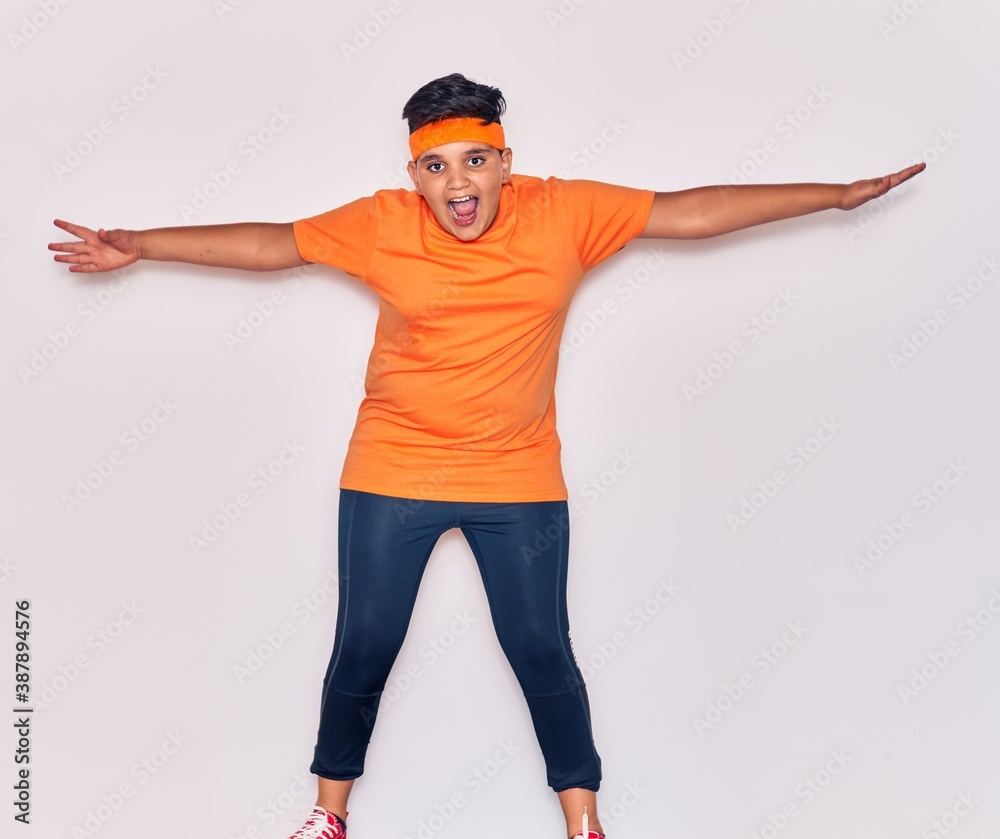 Adorable hispanic kid wearing sportswear smiling happy. Jumping with smile on face over isolated white background Adorable hispanic kid wearing sportswear smiling happy. Jumping with smile on face over isolated white background