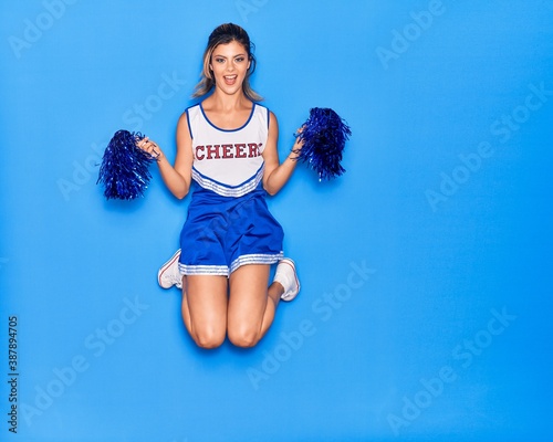 Foto Young beautiful girl wearing cheerleader uniform smiling happy