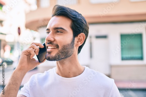 Young hispanic man smiling happy talking on the smartphone at city.