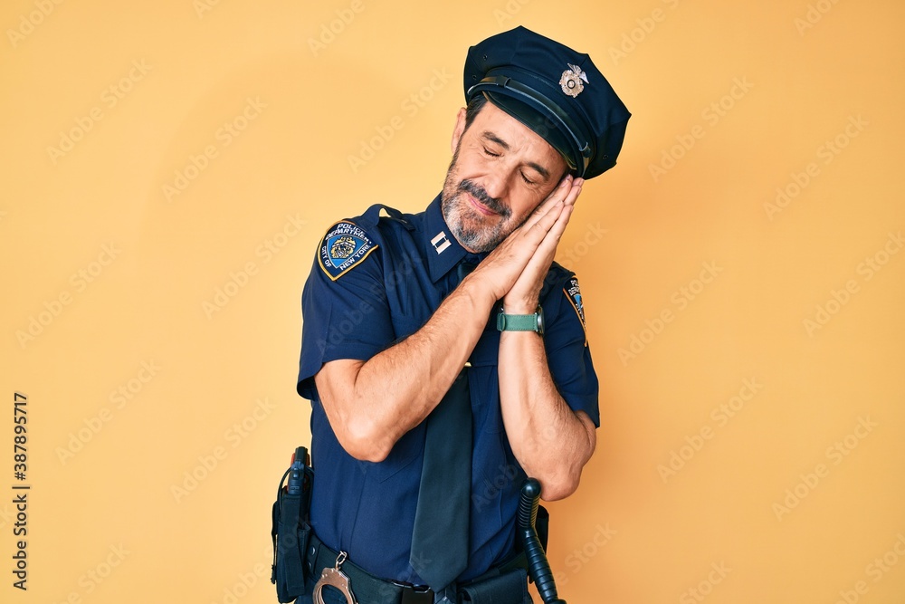 Middle age hispanic man wearing police uniform sleeping tired dreaming and posing with hands together while smiling with closed eyes. Middle age hispanic man wearing police uniform sleeping tired dreaming and posing with hands together while smiling with closed eyes.