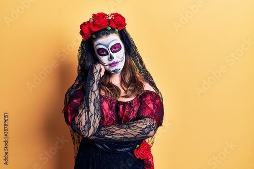 Young woman wearing day of the dead costume over yellow thinking looking tired and bored with depression problems with crossed arms.