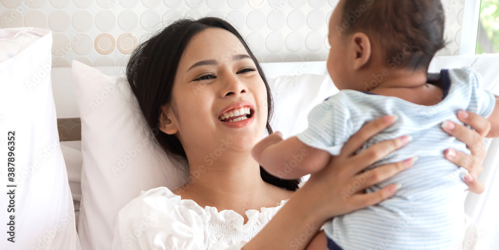 Portrait of enjoy happy love family asian mother playing with adorable little asian baby.Mom touching with cute son moments good time in a white bedroom.Love of family concept Portrait of enjoy happy love family asian mother playing with adorable little asian baby.Mom touching with cute son moments good time in a white bedroom.Love of family concept