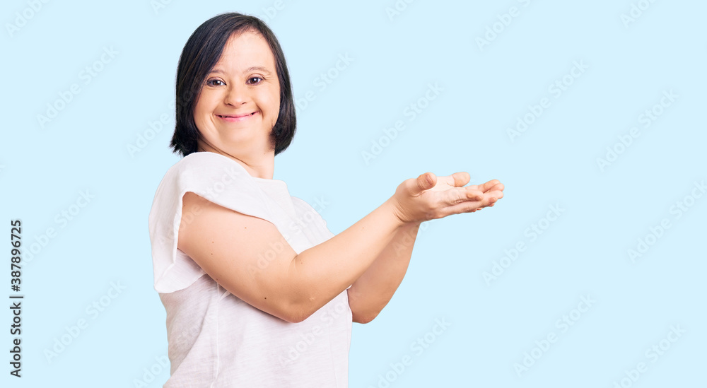 Brunette woman with down syndrome wearing casual white tshirt pointing aside with hands open palms showing copy space, presenting advertisement smiling excited happy Brunette woman with down syndrome wearing casual white tshirt pointing aside with hands open palms showing copy space, presenting advertisement smiling excited happy