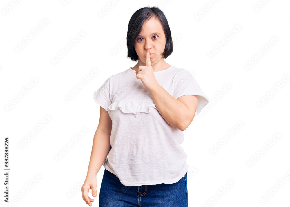 Brunette woman with down syndrome wearing casual white tshirt asking to be quiet with finger on lips. silence and secret concept. Brunette woman with down syndrome wearing casual white tshirt asking to be quiet with finger on lips. silence and secret concept.