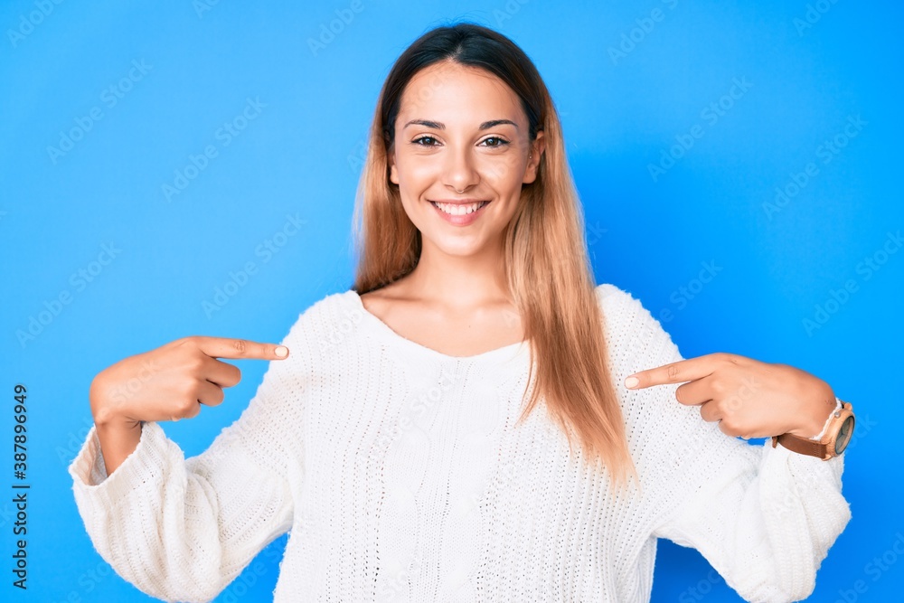 Fototapeta premium Young brunette woman wearing casual sweater looking confident with smile on face, pointing oneself with fingers proud and happy.