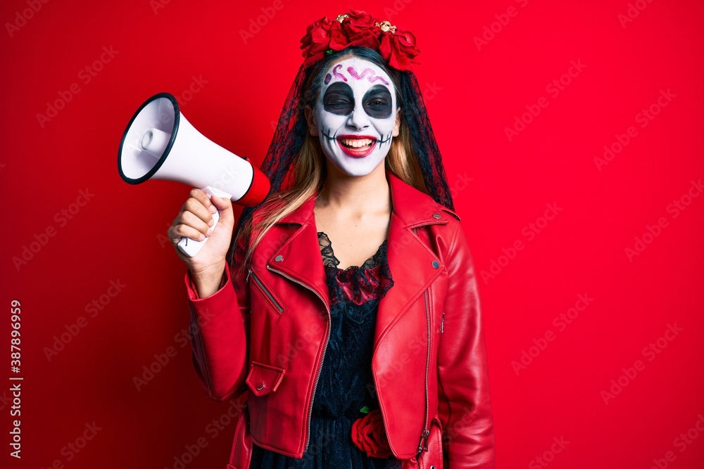Obraz premium Woman wearing day of the dead costume using megaphone winking looking at the camera with sexy expression, cheerful and happy face.
