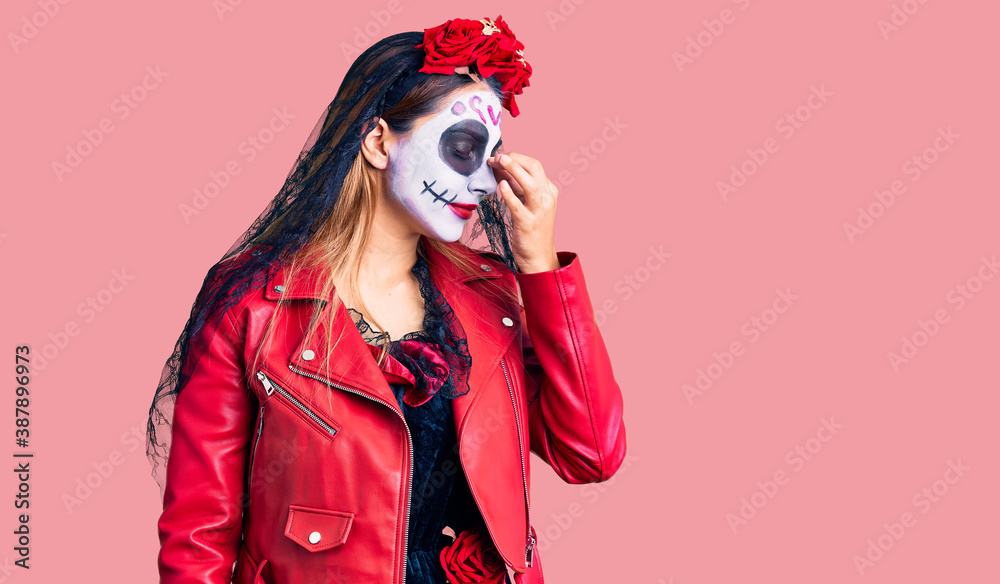 Obraz premium Woman wearing day of the dead costume over background tired rubbing nose and eyes feeling fatigue and headache. stress and frustration concept.