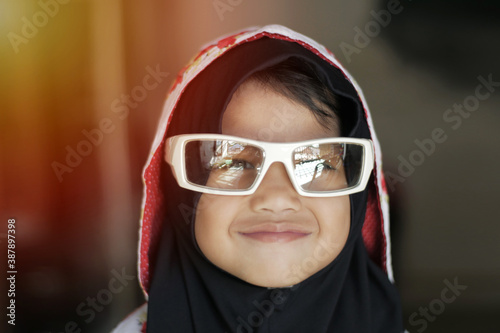 Cute adorable little baby girl looking at camera and smiling, happy Asian muslim girl wearing sunglasses © airdone