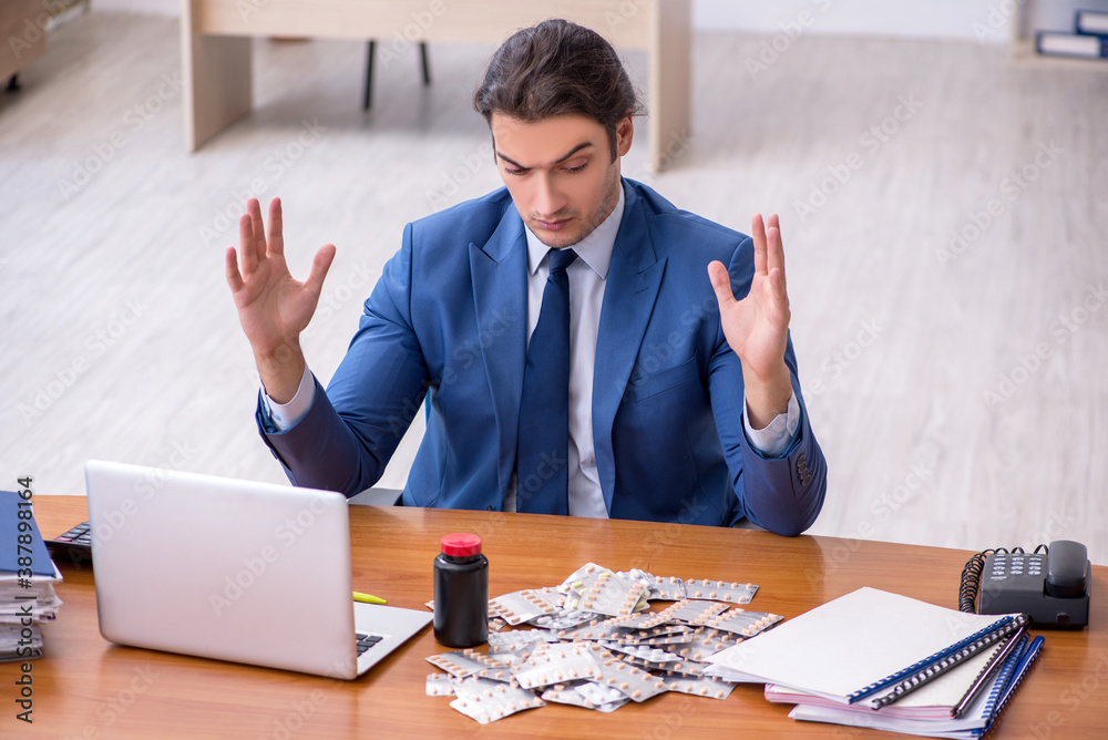Young male sick employee suffering at workplace Young male sick employee suffering at workplace