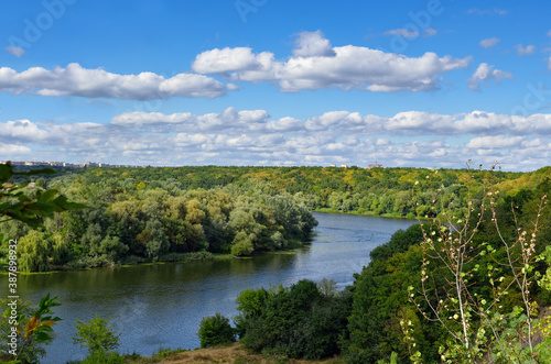 River among the wooded coasts against the blue sky