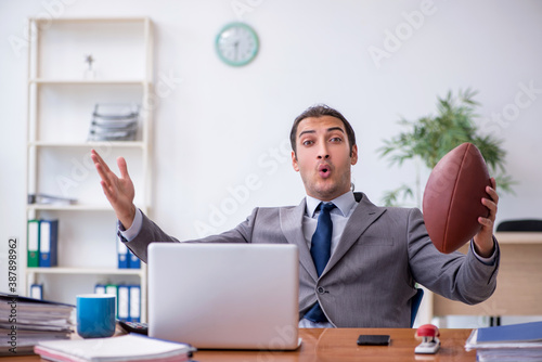 Young male employee with rugby ball in the office