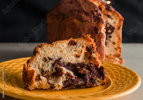 Traditional Christmas panettone (Chocottone) on yellow plate. Delicious panettone slice, traditional Italian dessert for Christmas. Close up photo