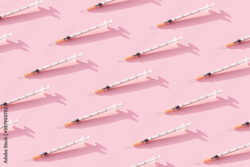 Creative medicinal pattern from syringes of pink background. Colorful concept of New Corona virus 2019-nCoV or COVID-19 vaccine. Flat lay, top view. Creative medicinal pattern from syringes of pink background. Colorful concept of New Corona virus 2019-nCoV or COVID-19 vaccine. Flat lay, top view.