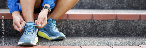 Running shoes. close up male athlete tying laces for jogging on road. Runner ties getting ready for training. Sport lifestyle. copy space banner.