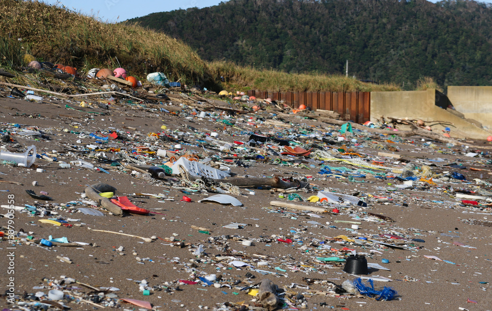 Summer sand beach landscape covered in colourful plastic waste