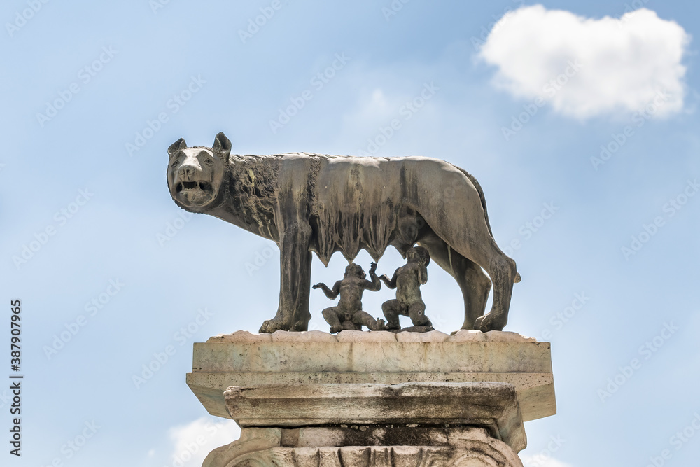 The bronze statue of the Capitoline Wolf feeding Romulus and Remus against blue sky in Rome, Italy