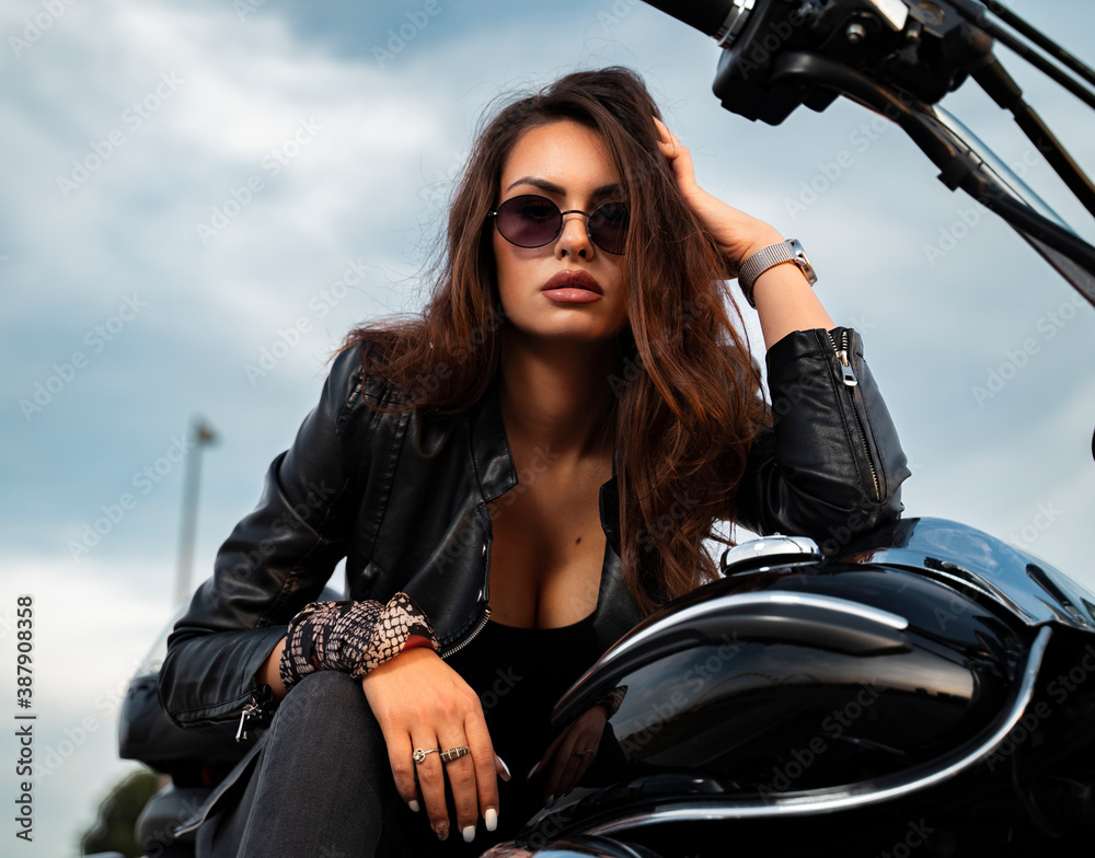 Closeup portrait of attractive, sensual girl in leather jacket posing on motorcycle - obrazy, fototapety, plakaty 