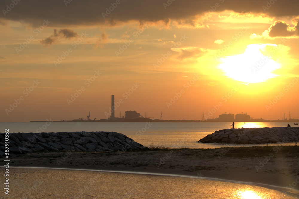 Warm sunset on a tropical beach over a power station