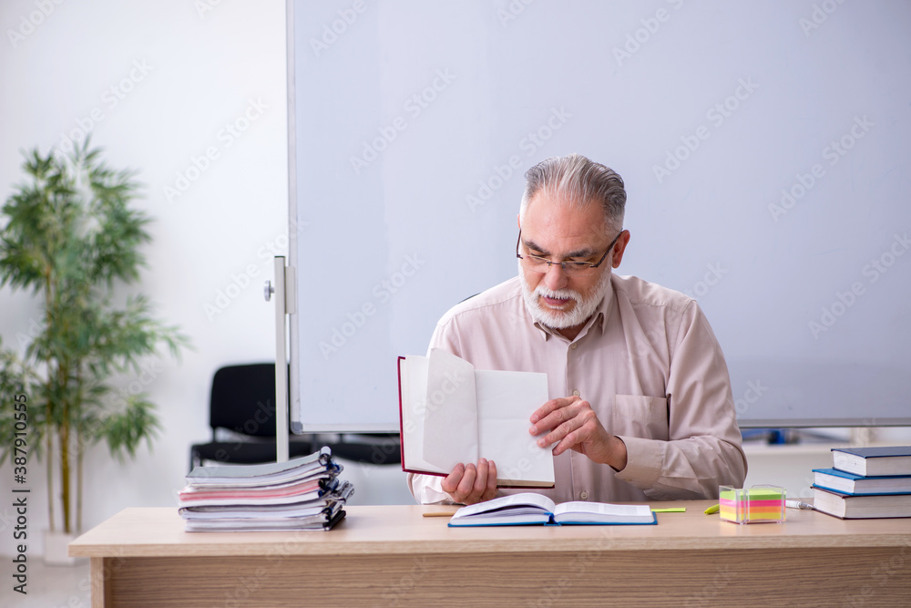 Old male teacher sitting in the classroom Old male teacher sitting in the classroom