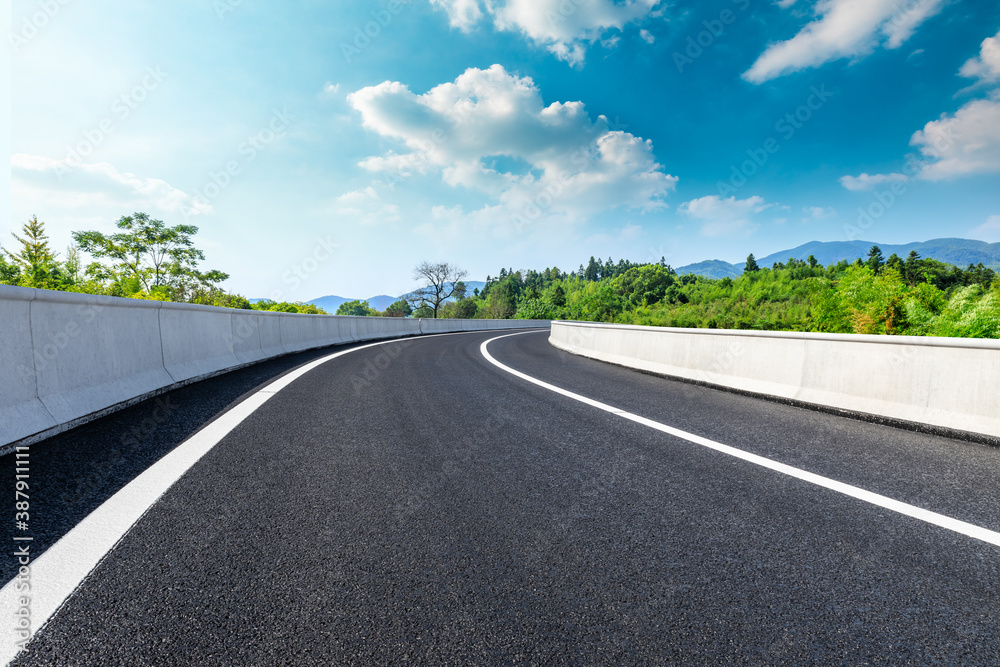 Asphalt road and green plants with mountain natural scenery in Hangzhou on a sunny day.