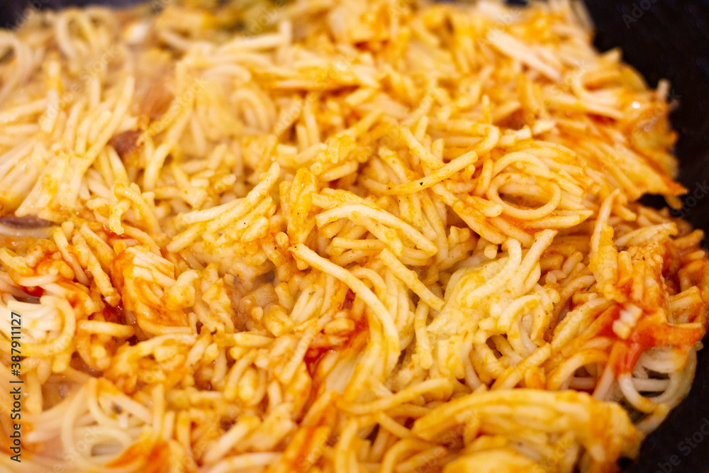 spaghetti mixed with fried tomato heating in a pan spaghetti mixed with fried tomato heating in a pan