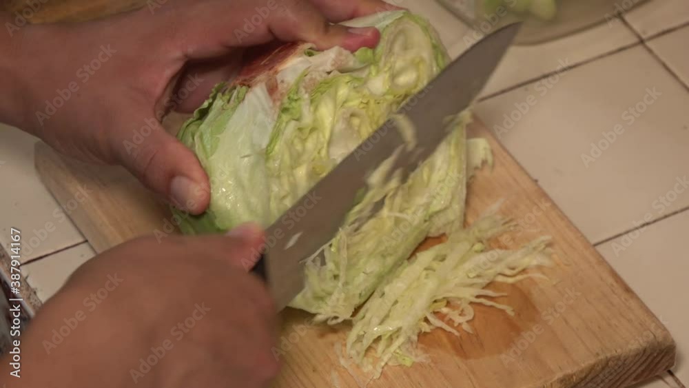 Hands shredding a lettuce on a cutting board. Hands shredding a lettuce on a cutting board.