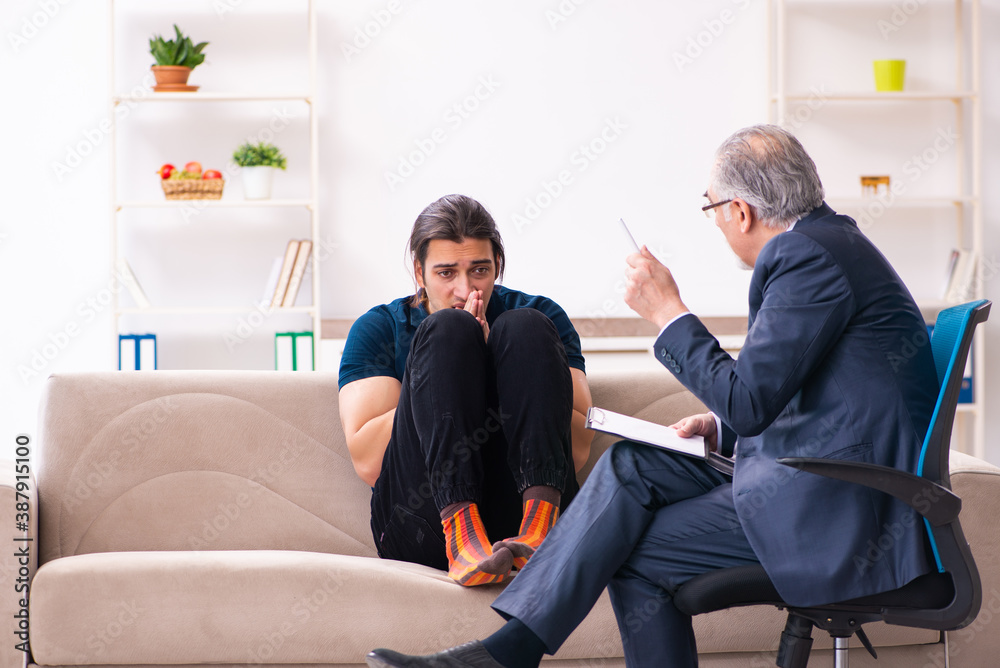 Young man visiting old male psychologist Young man visiting old male psychologist