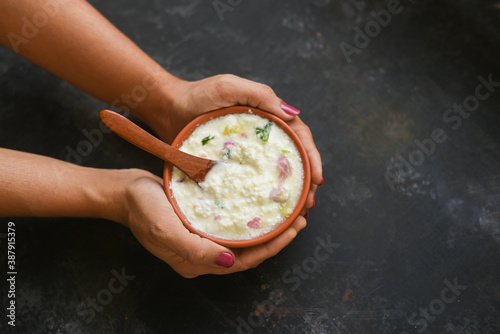 Bowl of homemade sour cream curd yogurt Dahi fresh herbs curry leaf Kerala, India. woman hand take dairy product obtained coagulating milk process curdling. probiotic food tasty curd rice curry spices photo